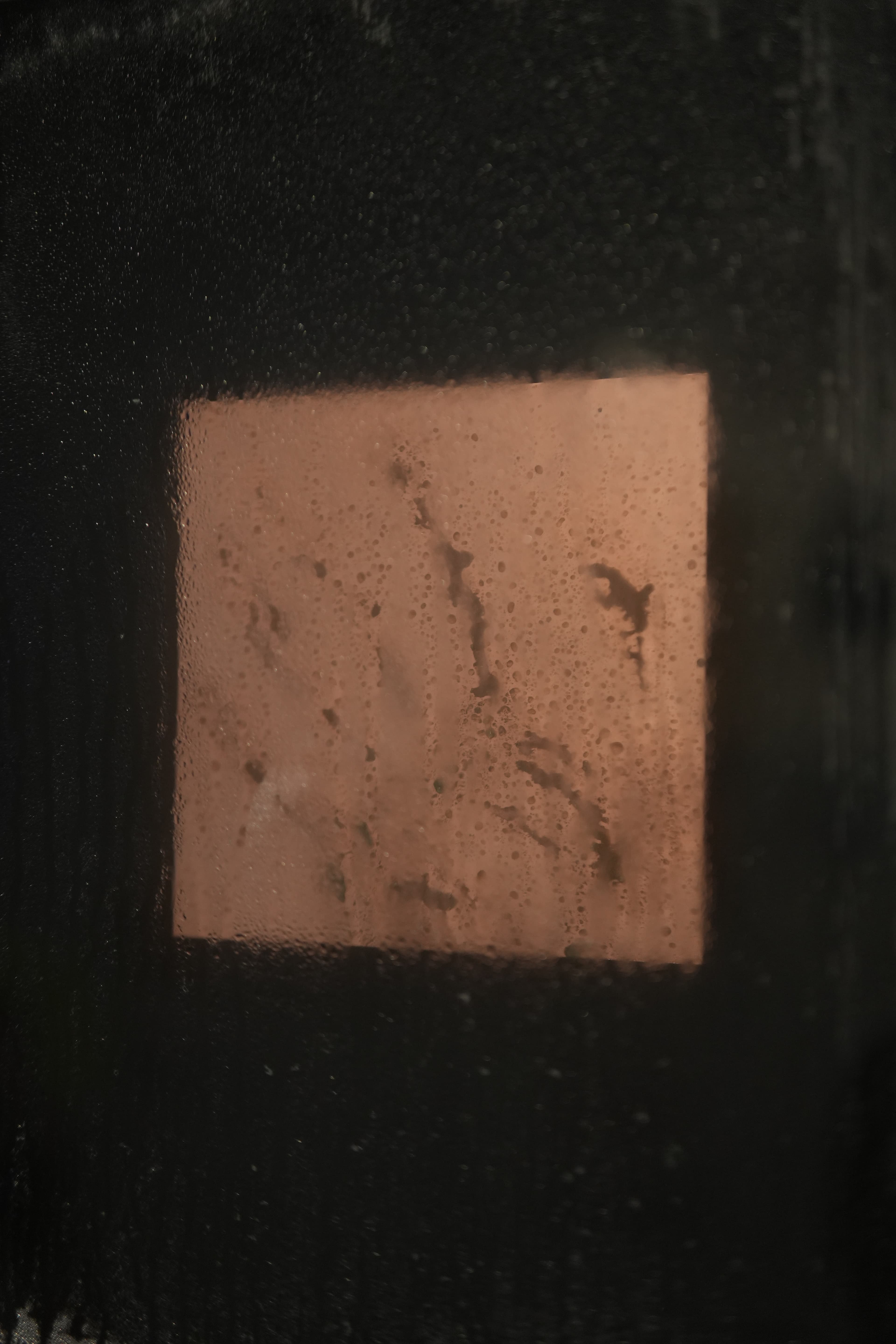 Copper plate visible through condensation on glass
